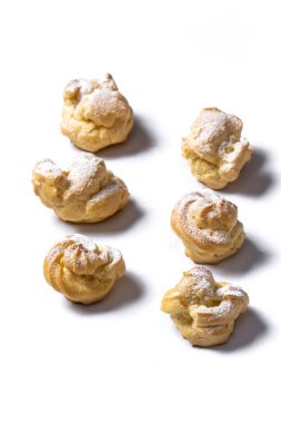Decorating profiteroles with powdered sugar. Eclairs with icing sugar
