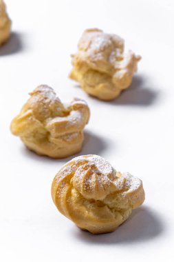 Decorating profiteroles with powdered sugar. Eclairs with icing sugar