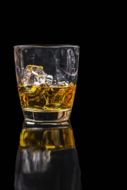 Whisky glass with ice cubes on black background