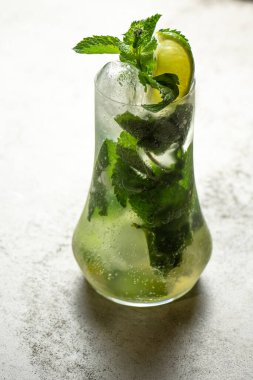 Limonlu mojito kokteyli ve gri taş arka planda viski bardağında nane şekeri..