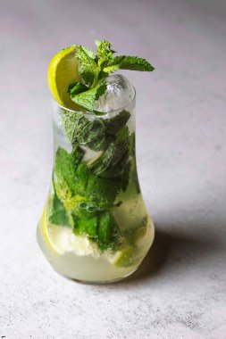 Limonlu mojito kokteyli ve gri taş arka planda viski bardağında nane şekeri..
