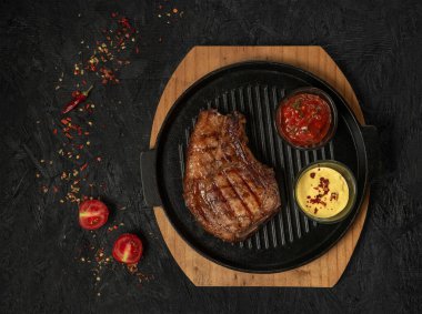 pork steak with vegetables in a black iron pan , top view.