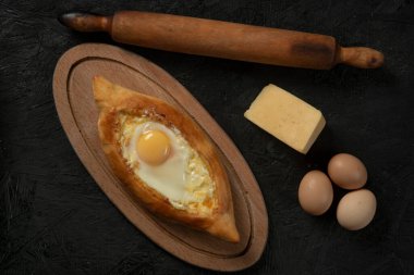 Kafkasya yassı ekmeği Adjarian khachapuri ve koyu bir tahta üzerinde yumurta. Adjarian Khachapuri Gürcistan peynirli ekmek