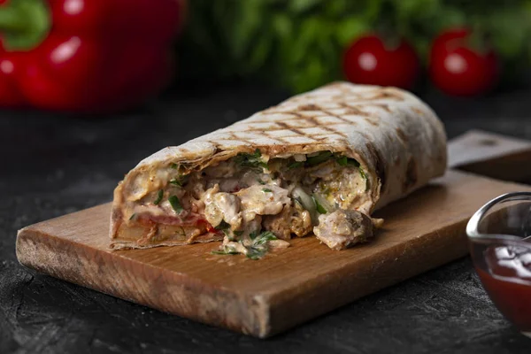 Shawarma sandviçi taze rulo, ızgara et ve siyah arka planda beyaz soslu salata..