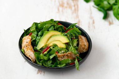 Siyah kasede avokadolu tavuk salatası. Sağlıklı yemek.