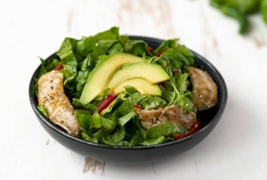 Siyah kasede avokadolu tavuk salatası. Sağlıklı yemek.