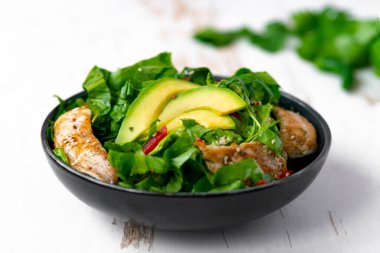 Siyah kasede avokadolu tavuk salatası. Sağlıklı yemek.