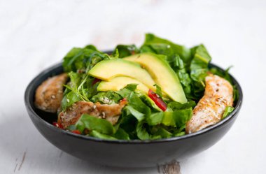 Sağlıklı sebze salatası, kızarmış tavuk, avokado, biber ve beyaz tabakta yaprak salatası..