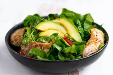 Siyah kasede avokadolu tavuk salatası. Sağlıklı yemek.