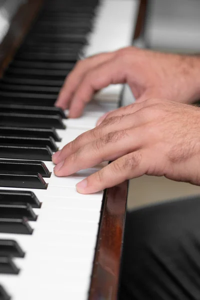 hands of a man playing piano .