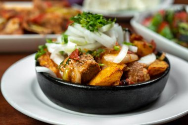 Beef stew with potatoes, carrots and herbs on black background with copy