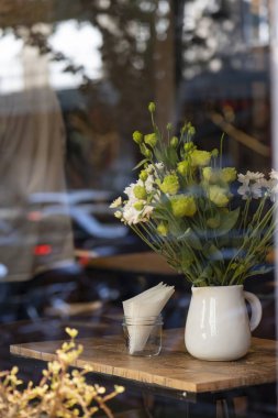 Kafenin camından süzülen vazodaki güzel çiçekler.