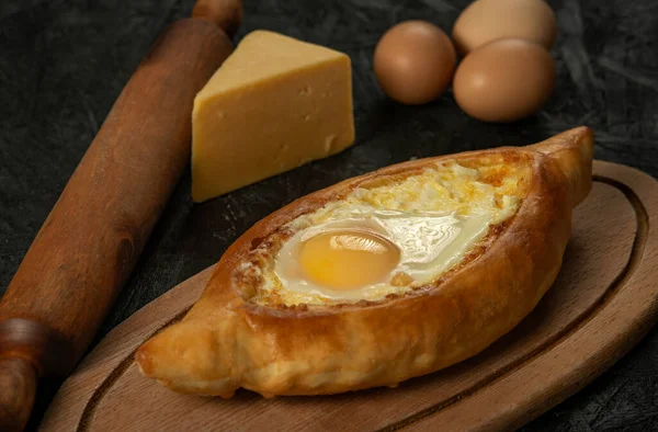 . Kafkas yassı ekmekleri, koyu bir ahşap üzerinde yumurtalı ekmekçi khachapuri. Adjarian Khachapuri Gürcistan peynirli ekmek