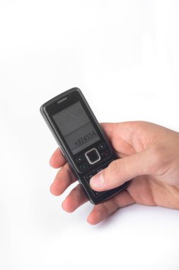 Eldeki eski düğmeli cep telefonu beyaz arkaplanda izole edilmiş, kırpma yolu dahil.