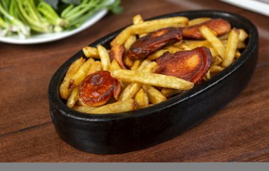 Frying pan with pieces fried sausage and potato