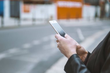 Kadın sokakta telefon tutarak. Cep telefonu ile yakın çekim kadının el