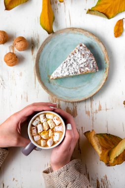 Pasta, ceviz ve saçılmış yapraklarla, sonbahar kompozisyonu eşliğinde eski püskü bir masada lokum tutan kadınların üst görüntüsü.