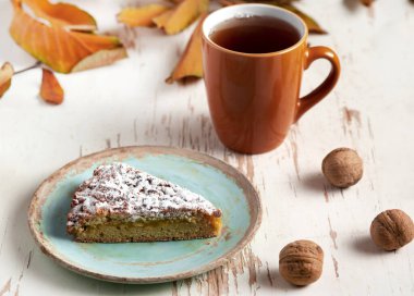 Kurumuş yapraklı ve cevizli sıcak çayla servis edilen fırında turta. Sonbahar kompozisyonu.