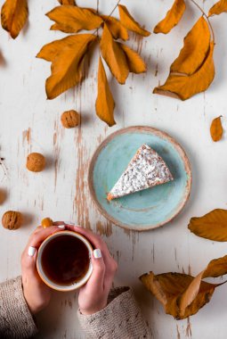 Sonbahar kompozisyonu bir fincan kahve, bir dilim turta ve beyaz ahşap arka planda kuru yapraklar. Sonbahar kompozisyonu.