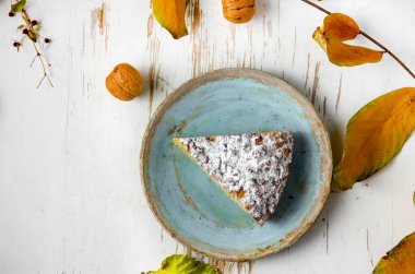 Dökük yapraklar ve cevizlerle, sonbahar kompozisyonu ile eski püskü masada servis edilen bir parça kek.