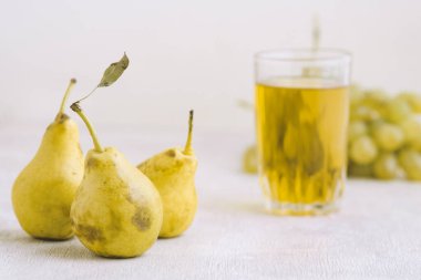 Beyaz ahşap arka planda bir bardakta armut suyu.