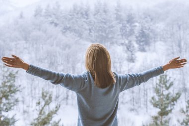 Kadın balkonda duruyor ve karlı dağlara bakıyor..