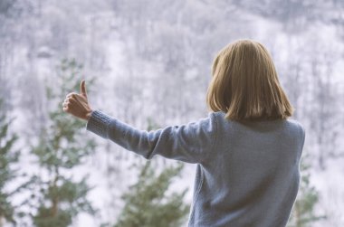 Kadın balkonda duruyor ve karlı dağlara bakıyor..