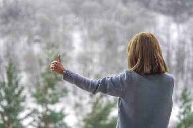 Kadın balkonda duruyor ve karlı dağlara bakıyor..