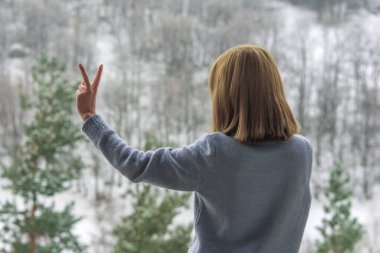 Kadın balkonda duruyor ve karlı dağlara bakıyor..
