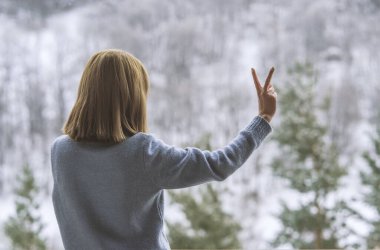Kadın balkonda duruyor ve karlı dağlara bakıyor..