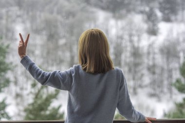 Kadın balkonda duruyor ve karlı dağlara bakıyor..