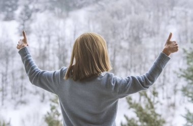 Kadın balkonda duruyor ve karlı dağlara bakıyor..