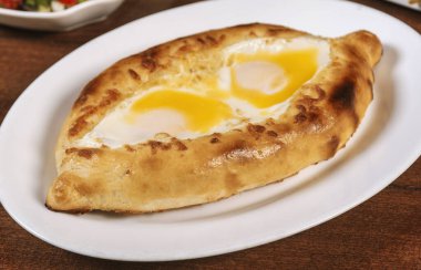 Adjarian veya Adjara Khachapuri 'de Khachapuri, tekne, Gürcistan mutfağı, peynirli ve yumurtalı hamur işi. Gürcü mutfağı..