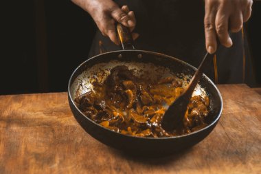 Aşçı eti sebzeli ve soğanlı bir kasede hazırlar. Doğu mutfağı.