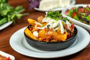 Beef stew with potatoes, carrots and herbs on black background with copy