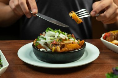 Man eating Beef stew with potatoes, carrots and herbs on black background with copy