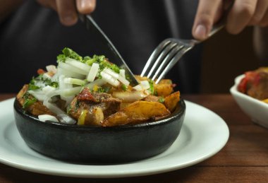 Man eating Beef stew with potatoes, carrots and herbs on black background with copy