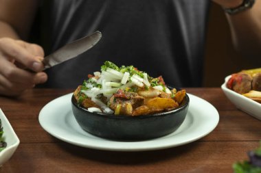 Man eating Beef stew with potatoes, carrots and herbs on black background with copy