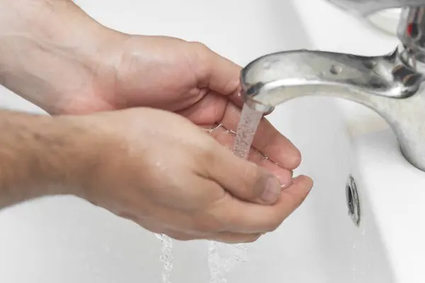 man washes his hands in the bathroom.The best protection against corona virus infection.Corona Virus pandemic protection by cleaning hands frequently.