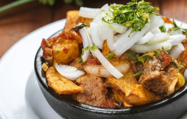 Beef stew with potatoes, carrots and herbs on black background with copy