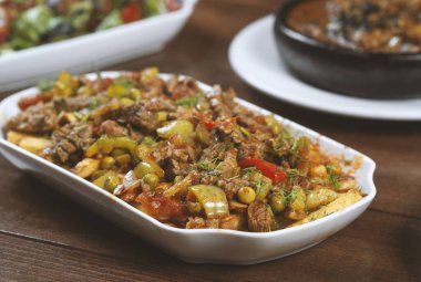 Beyaz bir tabakta sebze ve otlarla pişirilmiş biftek..