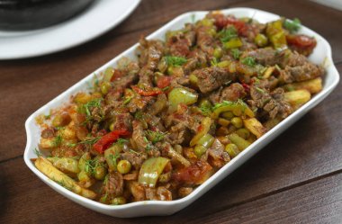 Beyaz bir tabakta sebze ve otlarla pişirilmiş biftek..