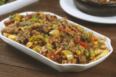 Beyaz bir tabakta sebze ve otlarla pişirilmiş biftek..