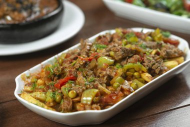 Beyaz bir tabakta sebze ve otlarla pişirilmiş biftek..