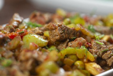 Beyaz bir tabakta sebze ve otlarla pişirilmiş biftek..