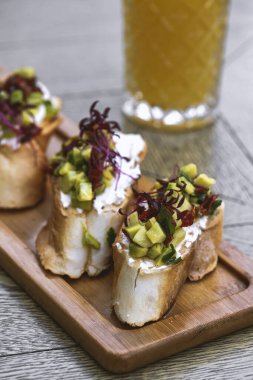 Avokadolu kanepeler, ahşap tahtada mozarella peyniri ve sos. bruschetta.