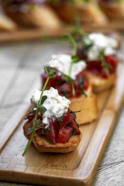 Domates, peynir ve ahşap tahtada otlar. Mozzarella ve roka. Kanepe