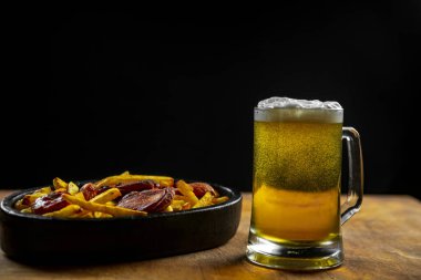 bira ve ahşap bir arka plan üzerinde patates ile kızarmış sosis ile bir bardak köpük. Oktoberfest.