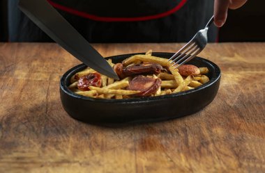 Demir bir tavada kızarmış sosis ve patates.