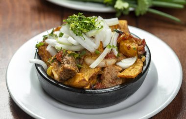 Beef stew with potatoes, carrots and herbs on black background with copy
